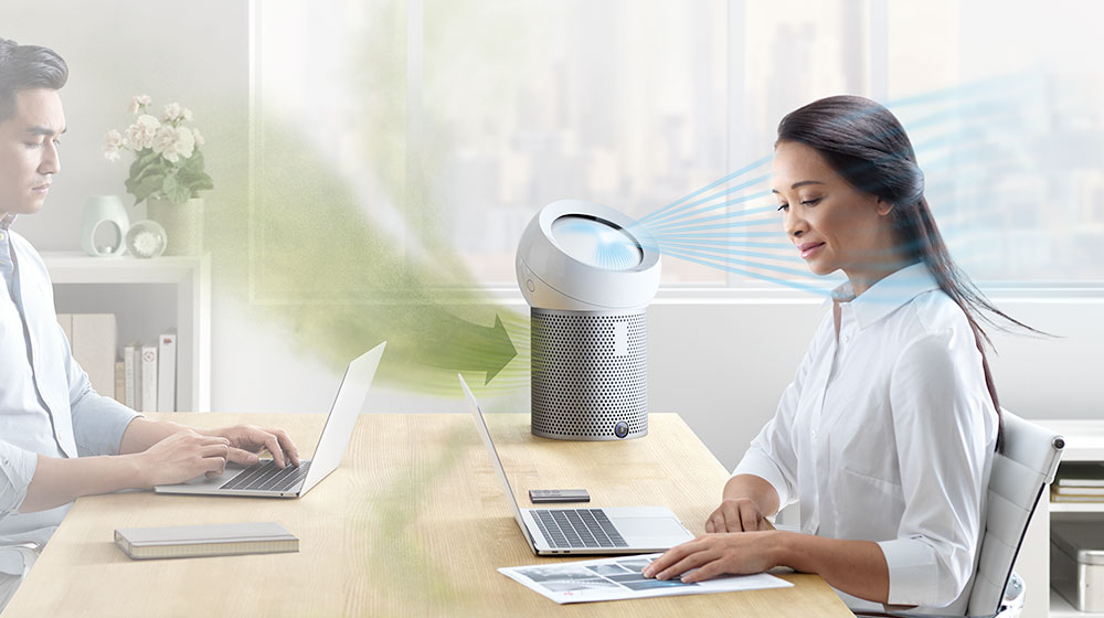 An office worker using a Dyson Pure Cool Me personal purifier fan
