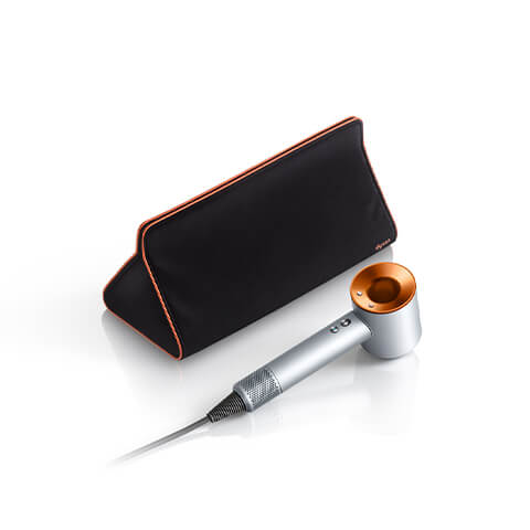 Triangular travel bag with silver copper Dyson Supersonic hair dryer in the foreground